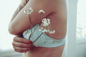 female torso with white bra and flowers in hand seen from the left side - Dr. Clearfield Reno NV - Cosmetic Surgery in Reno NV