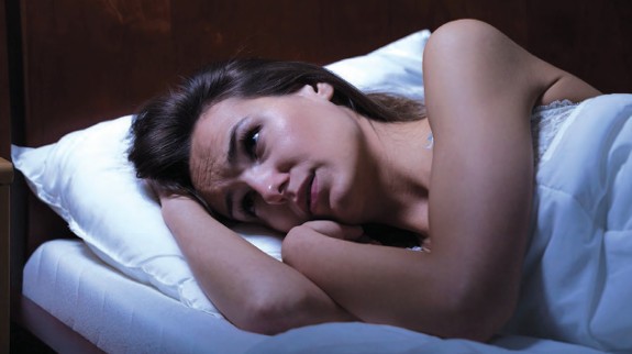 woman lying on her side on her bed - Adrenal Fatigue Reno NV